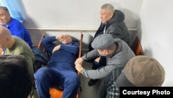 Bektur Asanov lies on a chair after one of the court hearings in the Kempir-Abad case.