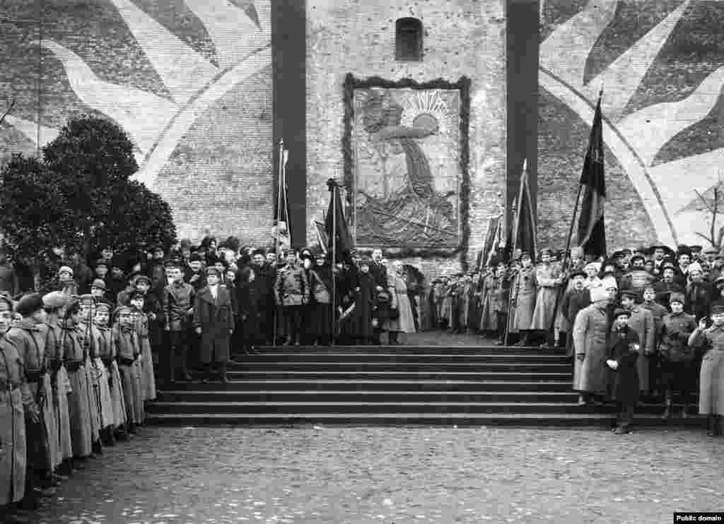 Bolsheviks at the opening to a memorial relief on the Kremlin walls. In the years immediately following the 1917 Bolshevik revolution, the site of today&rsquo;s mausoleum hosted this bas-relief that commemorated communists who were killed during the 1917 revolution and buried in mass graves at the base of the Kremlin walls. In this November 1918 photo, Vladimir Lenin (center left, touching cap) is standing on almost the exact spot where his embalmed corpse would be placed a few years later. &nbsp;