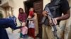 Police escort health workers as they administer polio vaccines to children in Karachi, Pakistan.