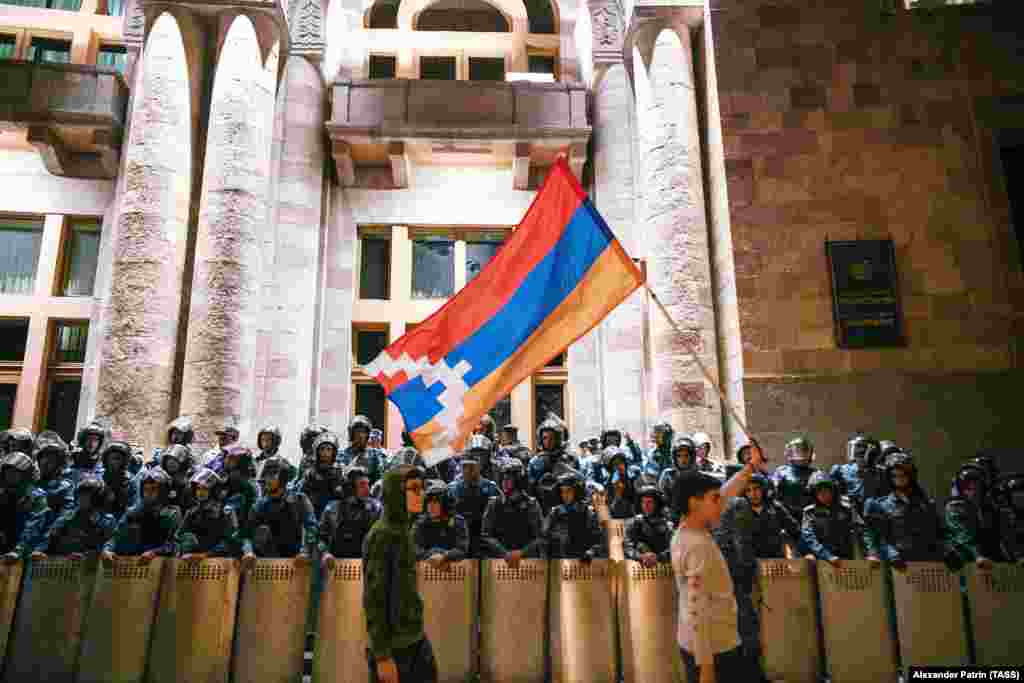 Young protesters wave the flag of the separatist Nagorno-Karabakh region in front of riot police guarding Armenia’s government building in Yerevan on September 22.