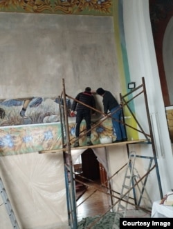 Workers obscuring the mural with white paint.