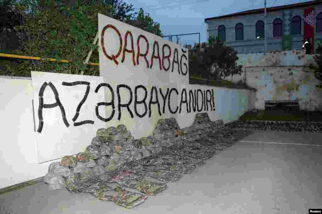 Uniforms of ethnic Armenian soldiers displayed under a sign made with automatic rifle magazines says "Karabakh is Azerbaijan!" in Susa, known as Shushi in Armenian. The military of the separatist region began to be disbanded after a September 20 agreement was reached between Azerbaijan and ethnic Armenian authorities. 