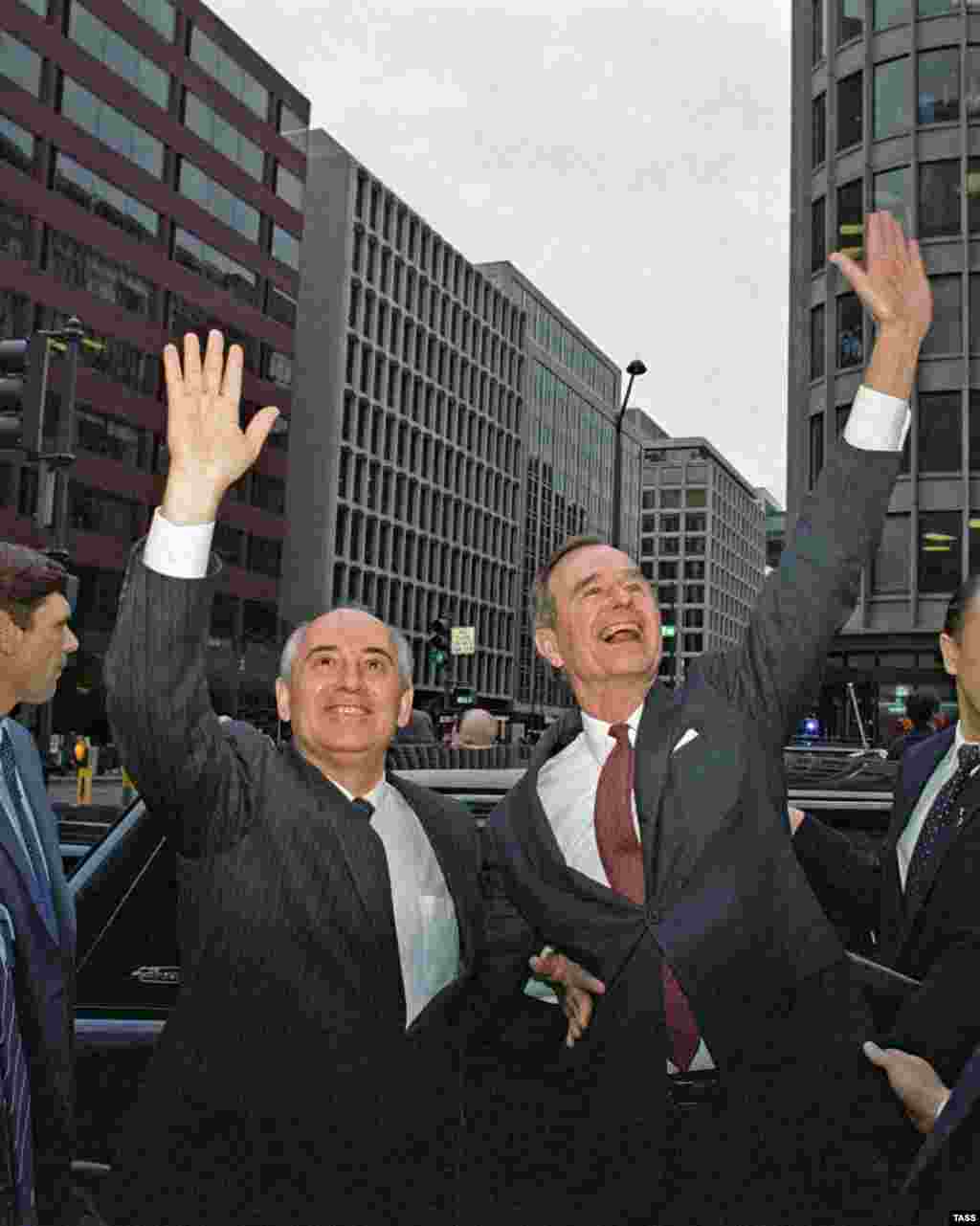 Gorbachev and U.S. Vice President George H.W. Bush wave to city residents in Washington, D.C., during an official visit on December 10, 1987.