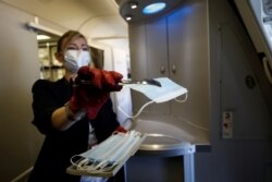 Бортпроводница Air France раздает маски пассажирам перед посадкой в самолет в аэропорту "Париж-Шарль-де-Голль"