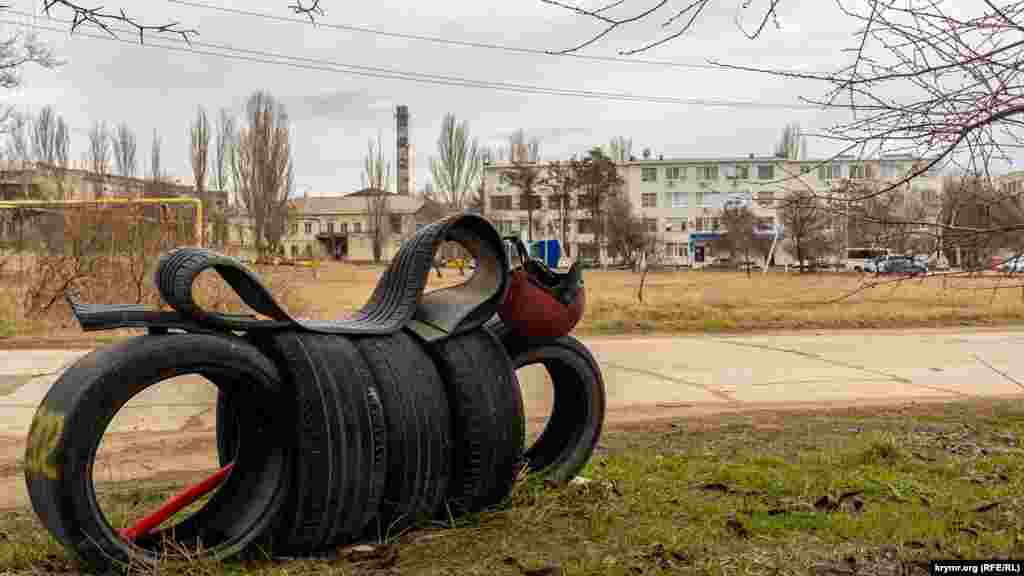 «Мотоцикл» з автомобільних шин на тлі виробничих корпусів «Брома» (ліворуч) та чотириповерхівки міжрайонної податкової інспекції