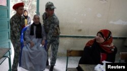 An elderly man is helped by army soldiers before casting his vote during Egypt's parliamentary elections last month. 