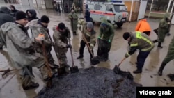 Workers in the Russia-occupied Crimean Peninsula collect oil from a fuel spill in December.