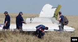 Australian and Dutch investigators examine a piece of debris of Malaysia Airlines Flight MH17 near the Ukrainian village of Hrabove.