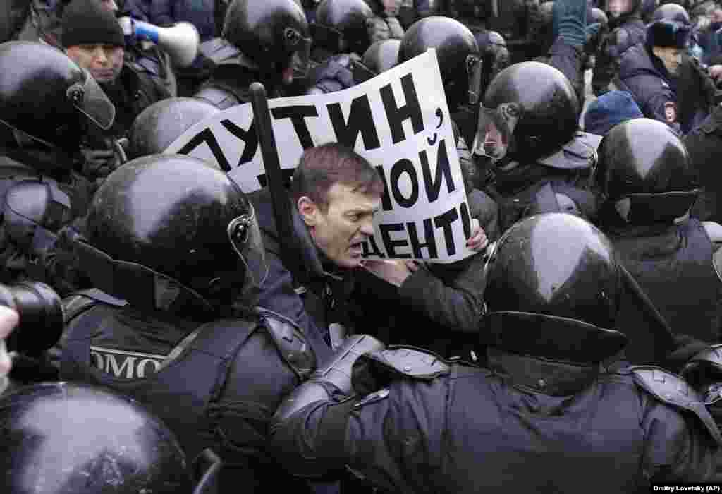 Poliția rusă reține un protestatar pe a cărui pancartă scrie &bdquo;Putin, nu ești președintele meu&rdquo; în timpul unui protest din Sankt Petersburg, pe 28 ianuarie, după ce autoritățile au respins candidatura unui lider al opoziției, Aleksei Navalny, la alegerile prezidențiale. Navalny a fost arestat la Moscova. La apelul acestuia, au avut loc demonstrații în mai multe orașe din țară. (AP/Dmitri Lovetsky)