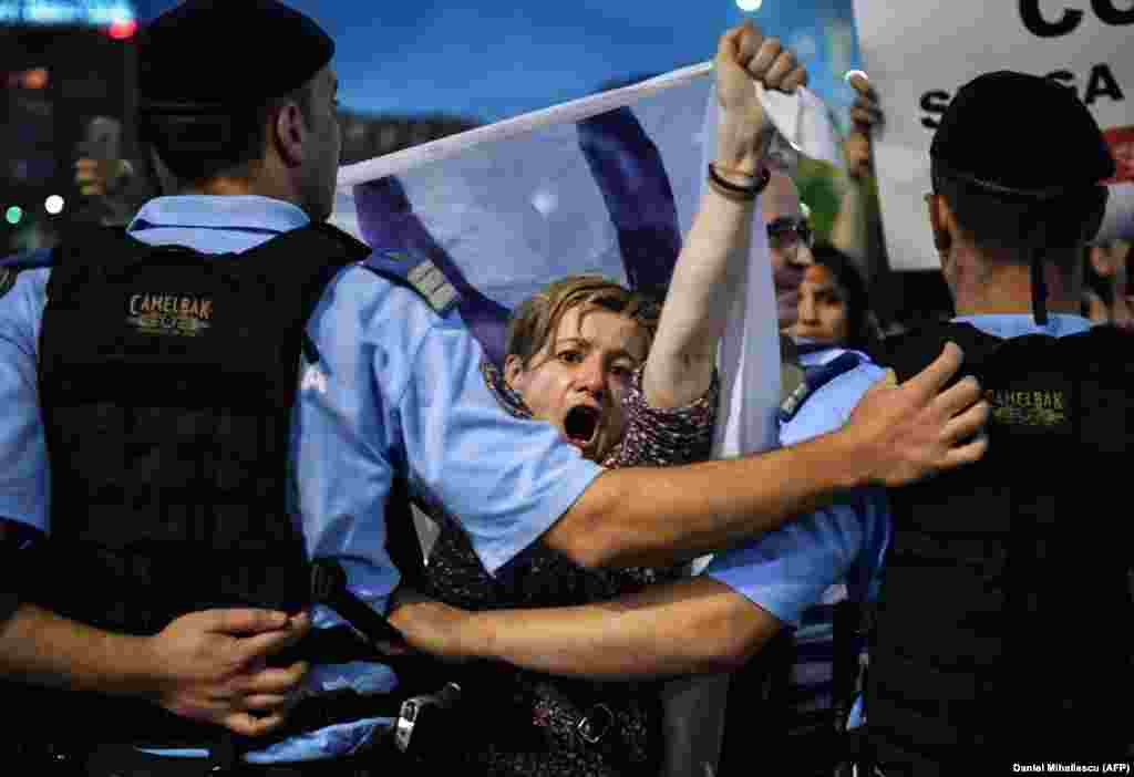 Protestatarii scandează sloganuri antiguvernamentale în timpul unui protest din fața Guvernului de la București, România, pe 30 mai. Aproximativ 2.000 de persoane s-au adunat pentru a protesta, după ce Curtea Constituțională a decis că președintele Klaus Iohannis trebuie să aprobe demiterea procurorului general anticorupție, Laura Kovesi. Guvernul a acuzat-o pe Kovesi de încălcarea Constituției, însă susținătorii ei spun că Laura Codruța Kovesi a fost demisă din cauza investigațiilor în rândul elitei politice a României. (AFP / Daniel Mihailescu)