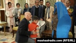 افغان ولسمشر شربت ګلې ته هرکلی وايي او زوی یې په غېږ کې نیولی