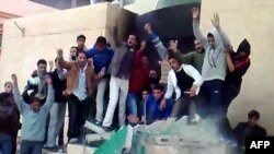 A video grab shows anti-government demonstrators destroying a monument in Tobruk, Libya