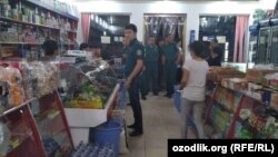 Сотрудники милиции требуют закрыть магазин «Диёра асал» в городе Газалкенте, 26 июля 2018 года. 