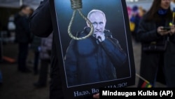 O pancartă care îl înfățișează pe președintele Rusiei, Vladimir Putin, afișată de un participant la protestul împotriva invaziei rusești în Ucraina, în fața Ambasadei ruse din Vilnius, pe 1 martie 2022.