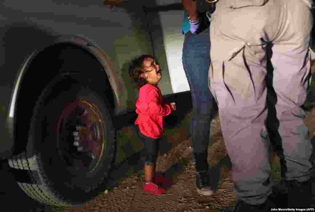 O fetiță refugiată din Honduras plânge în timp ce mama ei este percheziționată și reținută în apropierea graniței SUA-Mexic pe 12 iunie în McAllen, Texas. Solicitanții de azil au traversat Rio Grande din Mexic și au fost grănicerii americani înainte de a fi trimiși într-un centru de refugiați, unde sunt examinate cererile de azil. Serviciul american de frontieră a fost instruit să adopte o politică de "toleranță zero" față de imigranții fără acte. (/ Getty Images / AFP / John Moore)