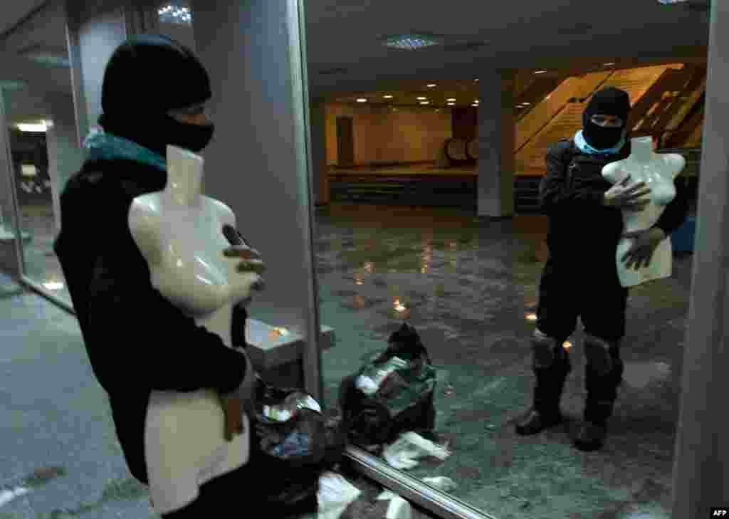 An opposition activist poses with a dummy in front of a mirror in Ukrainian House after protesters had taken over the building.