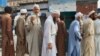 A man shows his ID card as he waits in line to vote in Pakistan's northwest on July 20.