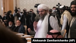 Former Afghan President Hamid Karzai, second left, looks as members of the Taliban delegation arrive for attending an international peace conference in Moscow on March 18.