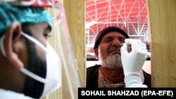 په اسلام اباد کې یو روغتیاپال د کورونا وایرس معاینې لپاره د یو کس له پوزې مایع اخلي - پخوانی انځور. 