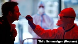 A medical employee collects a smear at a special coronavirus test center in Cologne, Germany.
