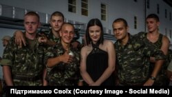Anastasia Prykhodko poses with Ukrainian soldiers on the front line.