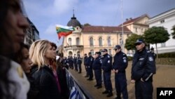 Демонстрацияга чыккан студенттер парламентин күзөткөн полициячылардын маңдайында турушат. 13-ноябрь 2013.