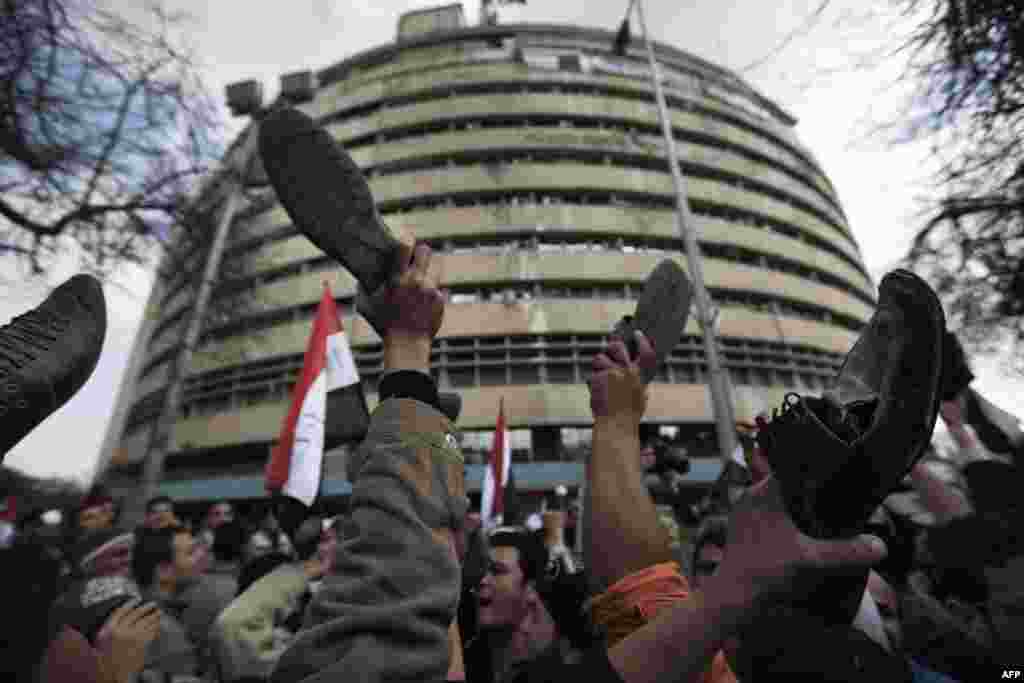 Protesters demonstrate by raising their shoes in front of the Egyptian national TV building in Cairo on February 11, 2011.