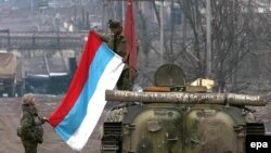 Russian soldiers unfold their flag in Grozny in 2000 