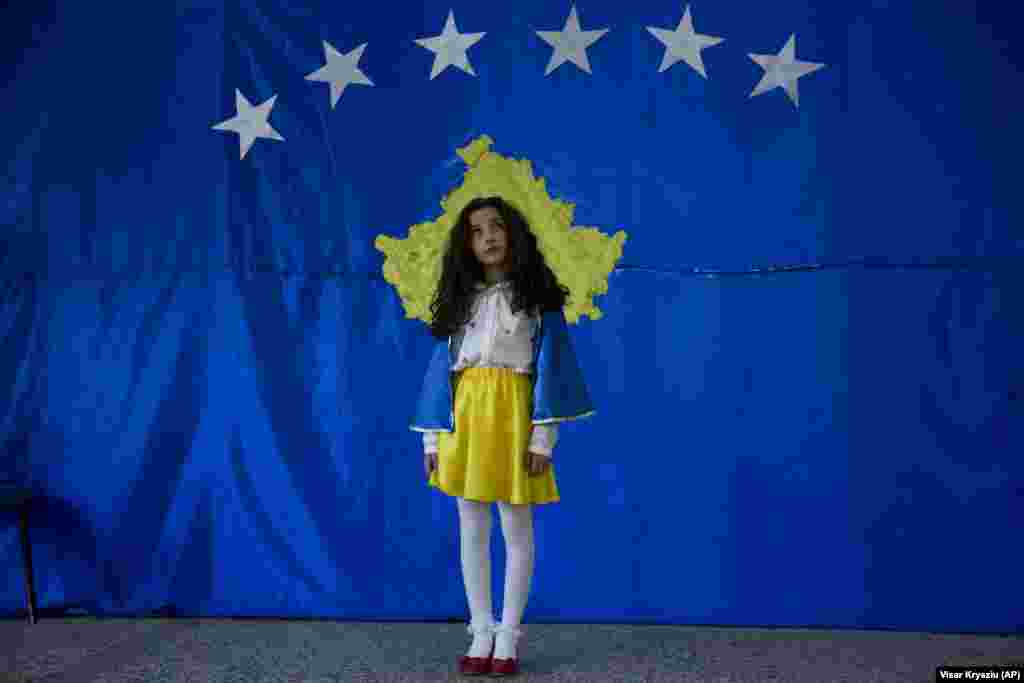Eleva Pavarsia Sopi, în vârstă de 10 ani, pozează în fața unui drapel kosovar în cadrul unei ceremonii marcând independența Kosovo, pe 16 februarie, într-o școală din satul Sllovi din apropierea orașului Lipjan, Kosovo. Pavaresia este primul copil născut după ce Kosovo și-a declarat independența de Serbia în 2008. Pavaresia se traduce în limba engleză ca &quot;independență&quot;. (AP / Visar Kryeziu)
