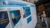 Женщина проходит мимо стенда с предвыборной агитацией кандидатов в президенты. Алматы, 14 мая 2019 года.