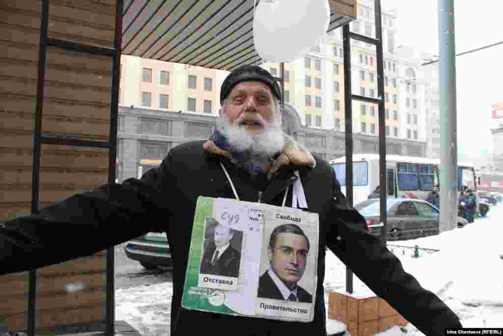 An elderly demonstrator wears a sign with pictures of Prime Minister Vladimir Putin and jailed ex-tycoon Mikhail Khodorkovsky. The former is accompanied by the words "Trial -- Resignation;" the latter reads "Government -- Freedom."