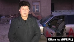 Kazakh activist Nurzhan Mukhammedov with his vandalized car in the background.